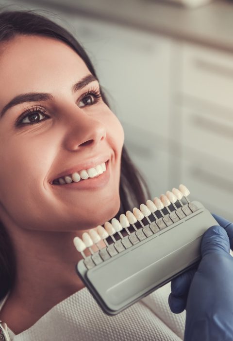 Beautiful young woman is sitting in dentist's chair while doctor is examining her teeth